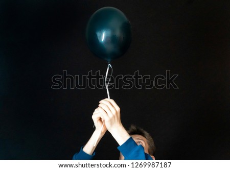 young male hold black baloon and going to fly with it