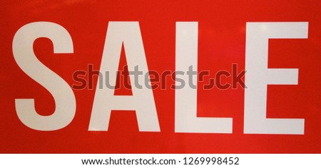 Red and white for sale sign promoting retail goods.
