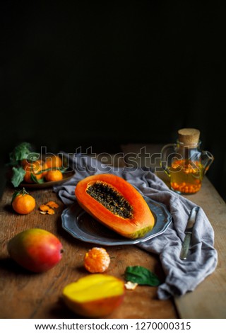 Exotic fruits with mandarins, mango, papaya on the black rustic background