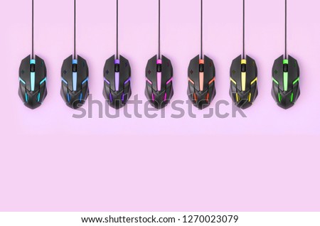 Black computer mouses hang on pastel pink background