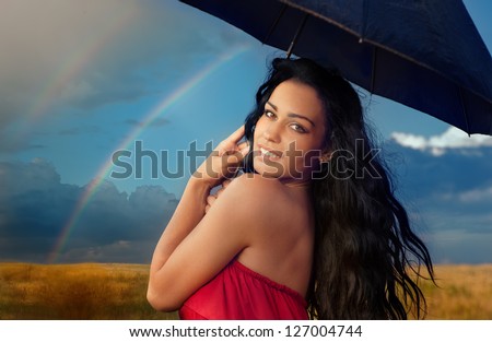 Portrait of beautiful young woman with umbrella on rainbow background