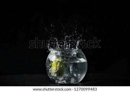 Key lime making a splash into a glass of water