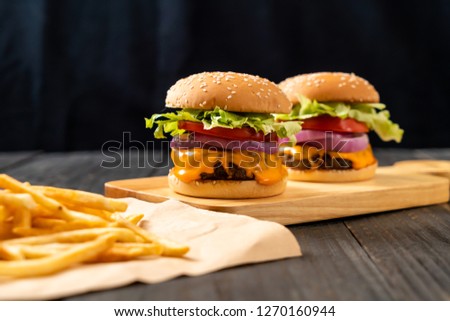 fresh tasty beef burger with cheese and french fries on wood background