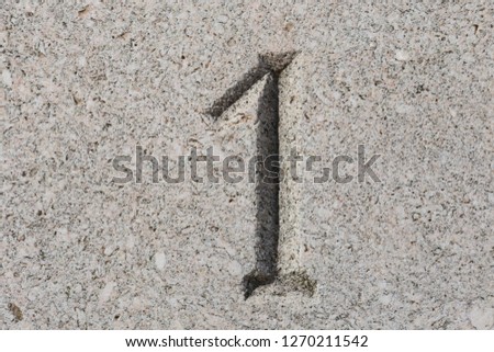 Close up outdoor view of number one engraved in grey stone. Gray textured surface with the sign 1. Abstract picture with a decorative numero.