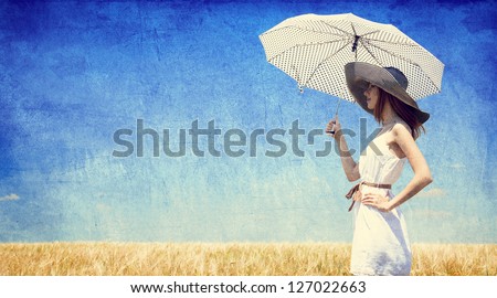 Women with umbrella at wheat field. Photo in old retro style.