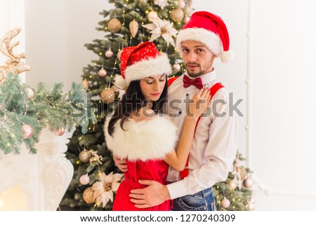 young pretty person with girlfriend in Christmas festive dress near Christmas tree and fireplace presents presents with festive mood