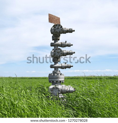 Canned oil well against the sky and field. Equipment of an oil well. Shutoff valves and service equipment.