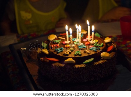 colorful birthday cake, with sweets and candles lit, to celebrate six years of my son