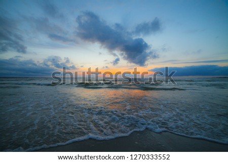 Calm Baltic sea at sunset with beautiful clouds and low waves
