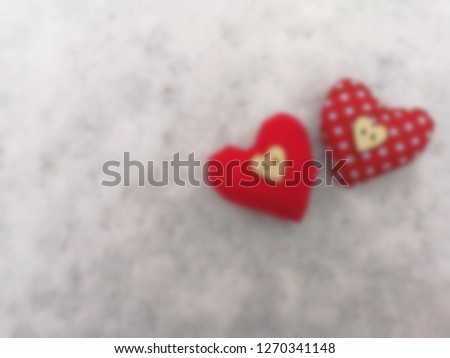 blur picture of two heart shape with red color and white polka dots on puffy white  snow and wooden bottons are on heart shape
