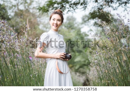Woman with a camera the middle of the meadow with violet flowers Murdannia Giganteum in Prachinburi, Thailand. Photographer in nature. 