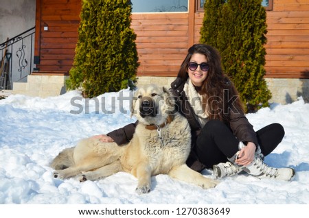 Beautiful Smiling Woman Playing with her Caucasian Shepherd Dog Outdoor in the  Winter.Owner and Dog Happy Together 