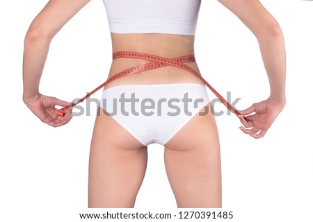 Beautiful fit female buttocks and croped body with measuring tape, isolated on white. Woman wears white base underwear, back view. Weight loss, dieting and anticellulite concept.