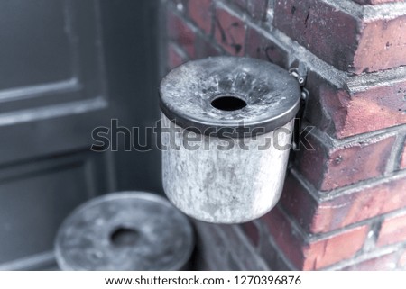 An old ashtray on a house wall in the house entrance. Concept: health or smoking