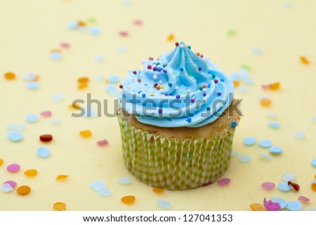 Image of a cupcake with blue whipped cream and sprinkles.
