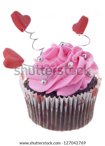 Close up image of chocolate cupcake with pink icing and heart shape decoration against white background
