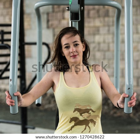 White teenage girl with brown hair doing a chest press workout 