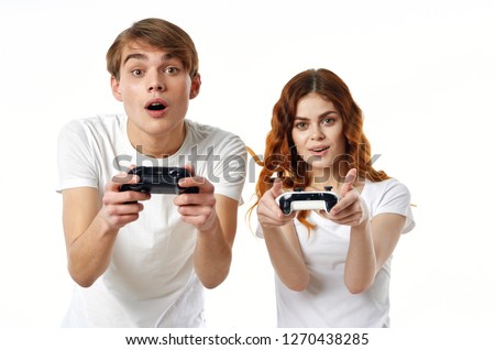 Man and woman with gaming joysticks in white shirts posing on an isolated white background