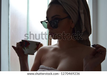 Attractive woman drinking coffee or tea at home with sunlight which passes trough window. Image 