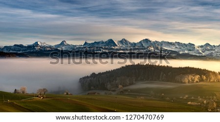 Impressive mountain range of switzerland covered in snow during a foggy day in winter.