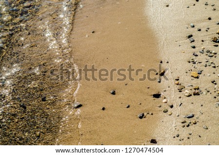 Beautiful texture of nature. Beautiful background and view of the texture of the sea, river and lake smooth surface of transparent water with a sand and stone shore in the afternoon.