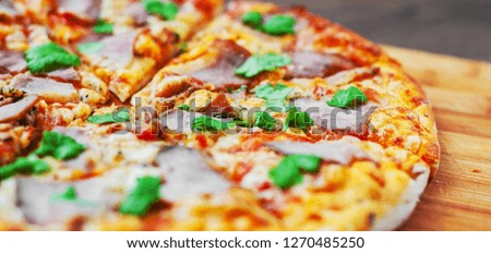 Pizza with Mozzarella cheese, ham, pepper, meat, Tomato sauce, Spices and Fresh Basil. Italian pizza on wooden background