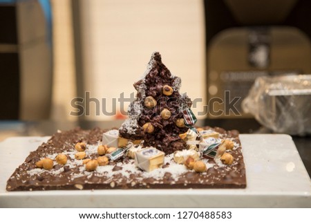horizontal image with detail of a Christmas tree made entirely of chocolate with hazelnuts in a pastry shop