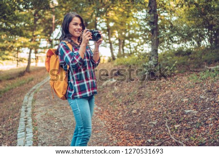 Young woman enjoys walking in the forest.At the same time he takes pictures of the forest.