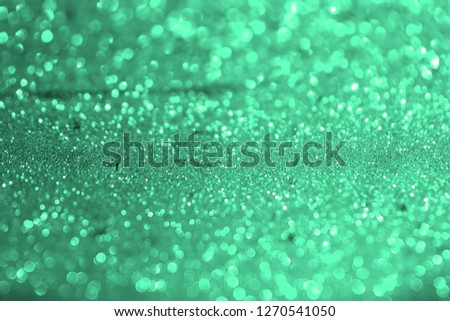 cute teal, sea-green glossy metallic sand made of glitters - festive concept with bokeh texture - abstract photo background