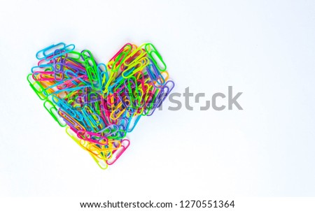 Paper clips lined in heart shape on white background