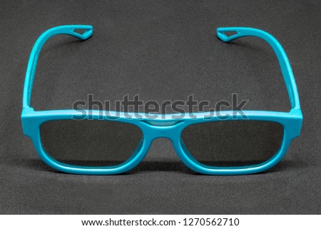 Light Blue 3 Dimensional glasses on a dark grey background