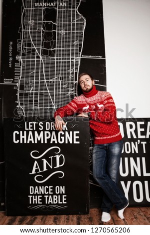 a man in a red sweater in a Studio by the wall with a black picture