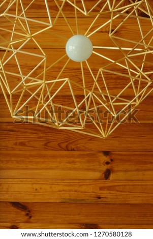 The ceiling lamp is made of straw. Hanging on the background of a wooden ceiling. Bottom view