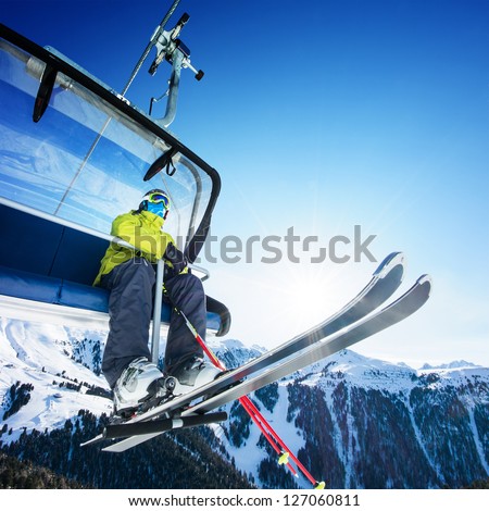 Skier sitting at ski lift in high mountains Royalty-Free Stock Photo #127060811