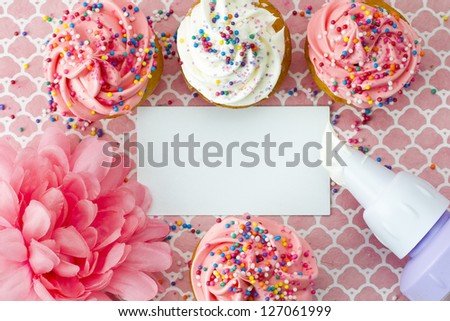 Close-up top view of strawberry cupcakes with empty placard and flower.