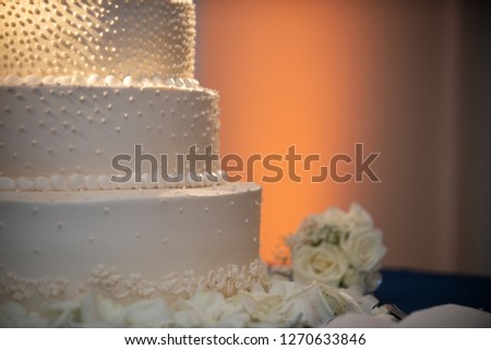 Three tier wedding cake with warm uplighting close up Royalty-Free Stock Photo #1270633846
