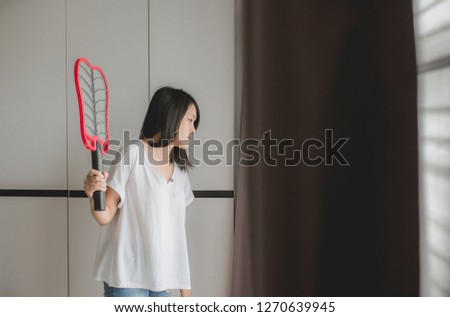Asian women using mosquito swatter at home,Female with mosquito electric net racket in bedroom