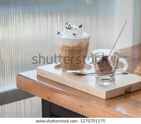 One glass of hot coffee with bear late art on top, serve on wood tray. Selective focus. 