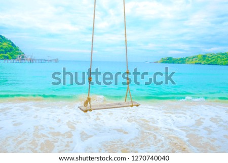 Wooden swing of beautiful tropical beach and blue sea on backdrop of mountains, sky and white clouds for travel and vacation in holiday relax time