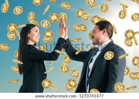 Businessman and woman celebrating golden bitcoin rain on sky background. Cryptocurrency and finance concept 