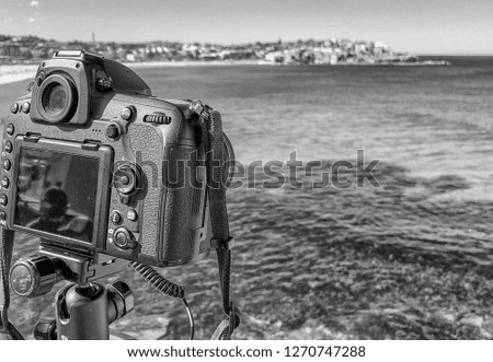 Modern camera on tripod taking pictures of beautiful beach and coastline.