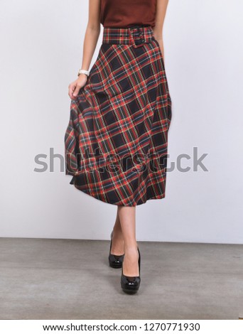 women in long checkered
skirt with black high hell shoes posing-gray background

