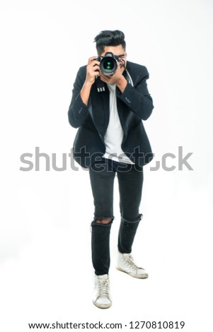 Full body length portrait indian man taking photo with dslr camera looking at camera isolated over white studio background.