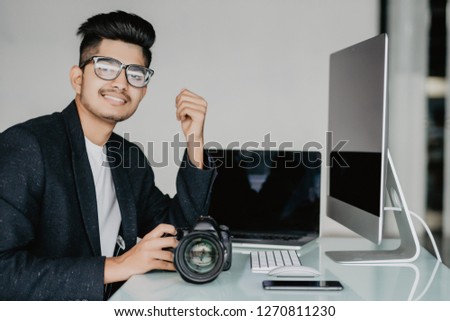 Side view portrait of young photographer sitiing near computer editing photos at desk at home, copy space