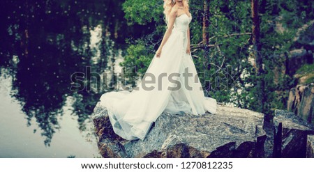 The bride with a bouquet on beautiful large lake background at sunset. Rustic Wedding