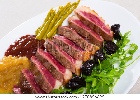 Delicious duck breast magret with prunes, pickled asparagus, fresh arugula