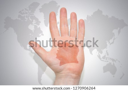 hand with map of cote divoire on the gray world map background. concept