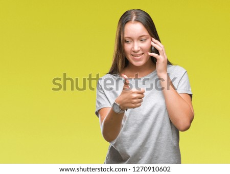 Young beautiful caucasian woman talking on smartphone over isolated background happy with big smile doing ok sign, thumb up with fingers, excellent sign