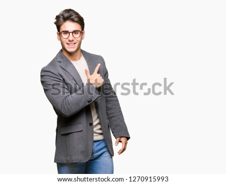 Young business man wearing glasses over isolated background cheerful with a smile of face pointing with hand and finger up to the side with happy and natural expression on face
