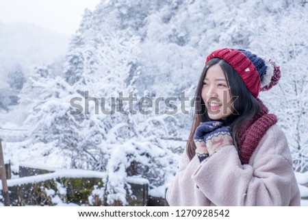 Asian Girl smile on photo with Shirakawa-go village in winter. Traditional village Houses Gassho style and one of UNESCO world heritage sites, Gifu, Japan